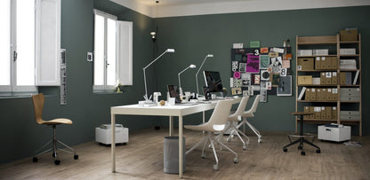 Estudio con paredes verdes, muebles de color blanco y un suelo de madera que realza la paleta de colores de la habitación.