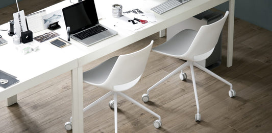 Área de juntas con un escritorio blanco y sillas, y un piso con acabado de madera.