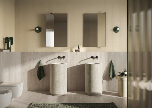 Baño en tonos beige con dos lavamanos cilíndricos, grifería en negro y un atractivo acabado de color amarillo vainilla en las paredes.