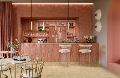 "Restaurante de estilo retro con acabados en tonos rosa, detalles en color rojo y toques de dorado."
